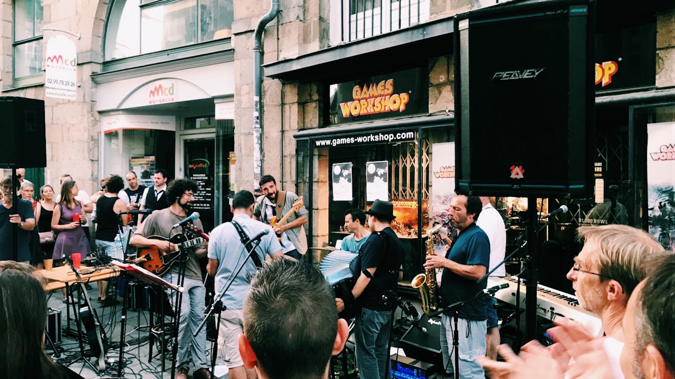 small band performing on street outside some shops